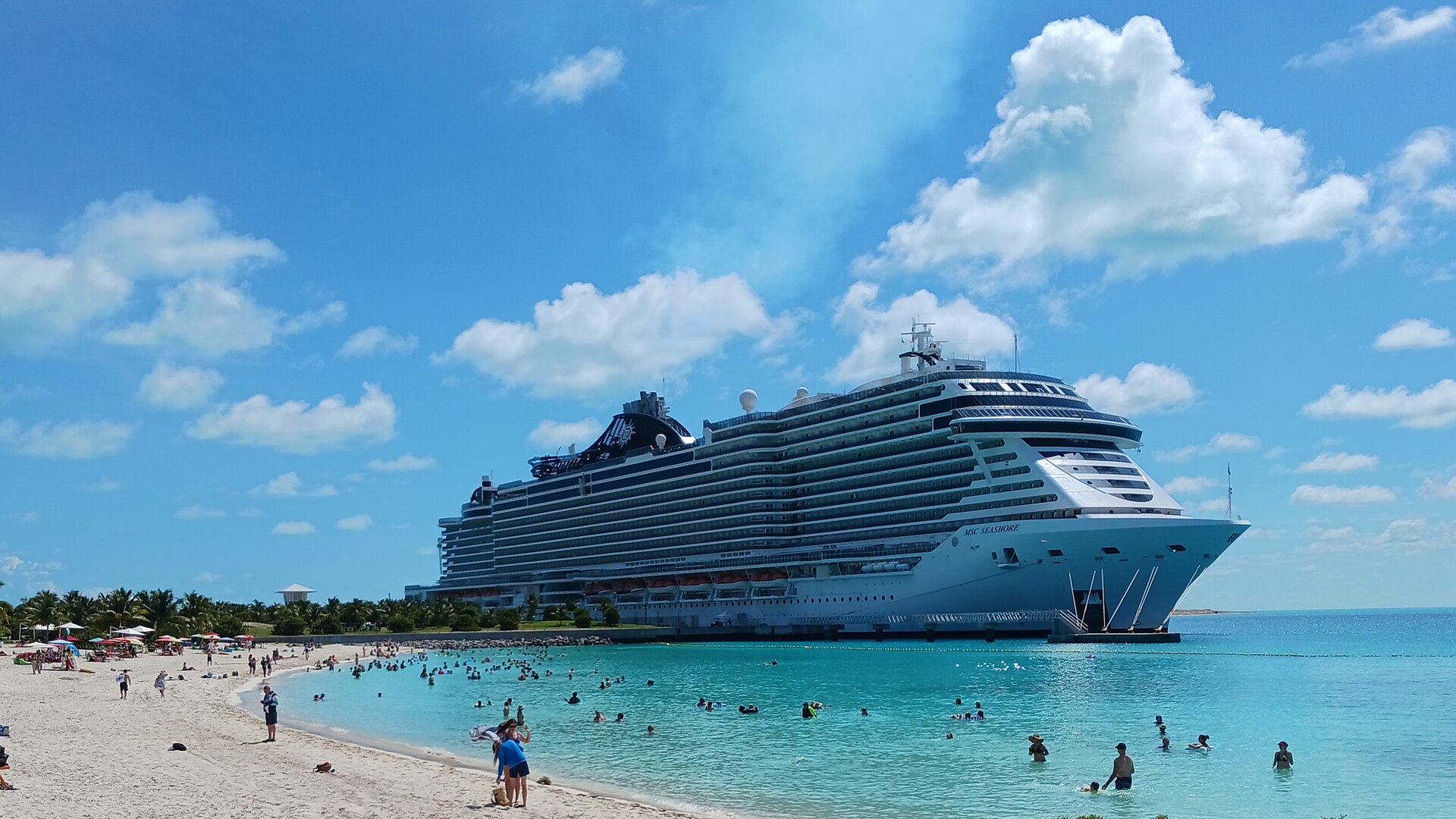 MSC Seashore docked beside a white beach and turquoise water at Ocean Cay in the Bahamas under a bright blue sky