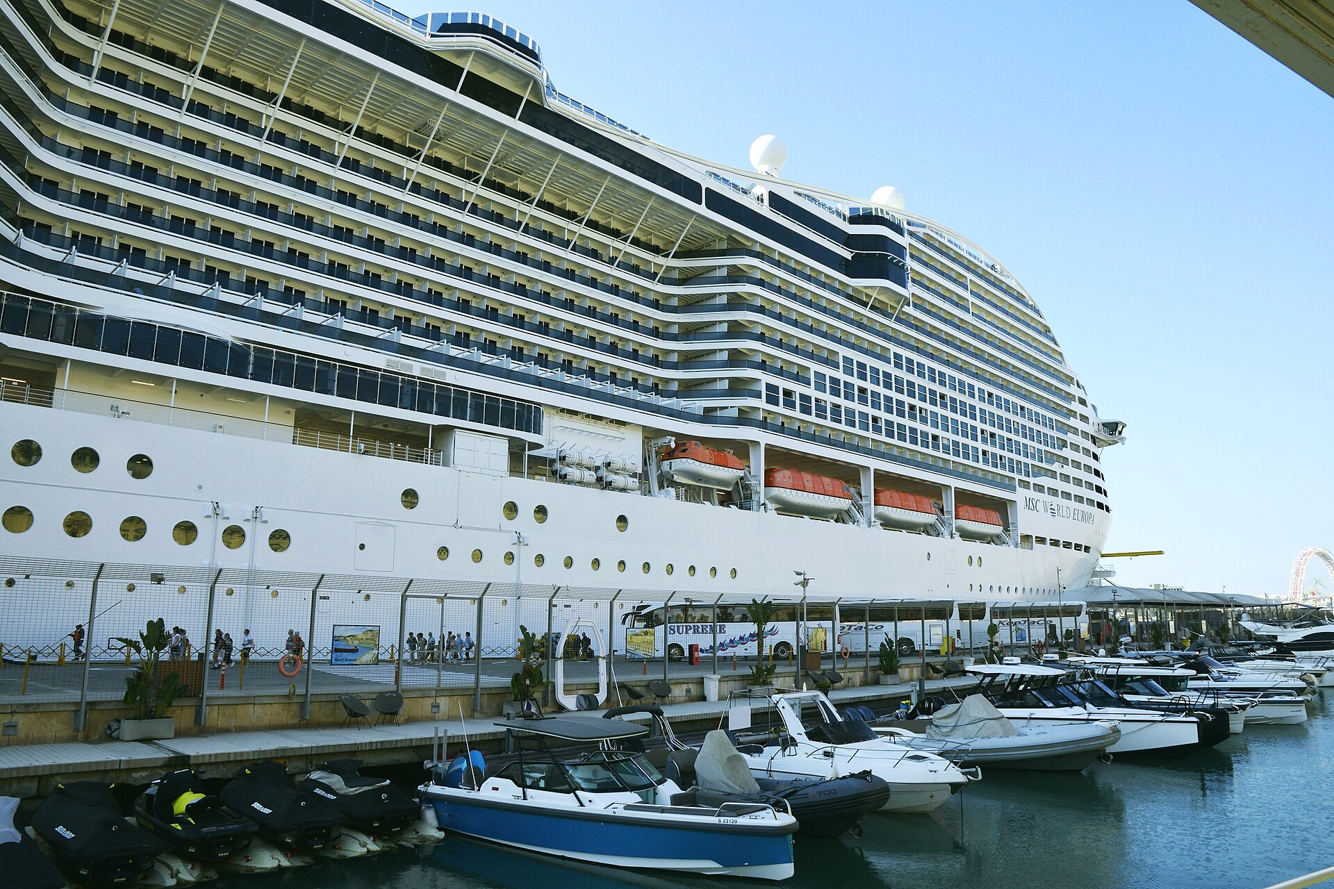 MSC World Europa docked beside a marina on a sunny day