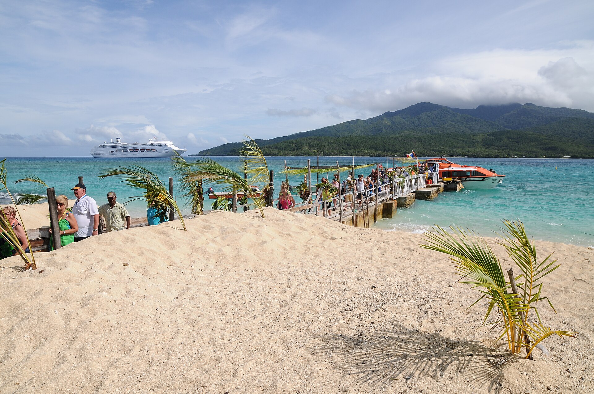 Cruise passengers on the white sand jetty at Mystery Island, Vanuatu, with a cruise ship anchored offshore