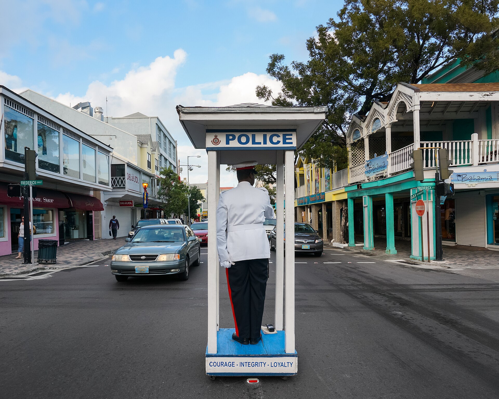 A Royal Bahamas Police Force officer in a white tunic directing traffic from a police stand at Bay Street and Frederick Street in Nassau
