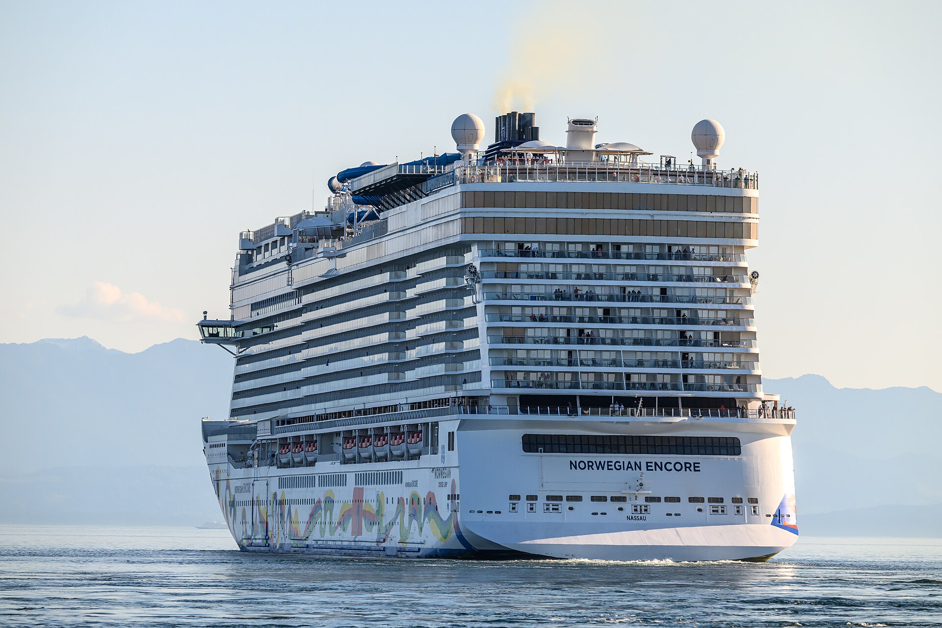 Norwegian Encore with colourful hull art sailing away from Victoria, British Columbia, at sunset