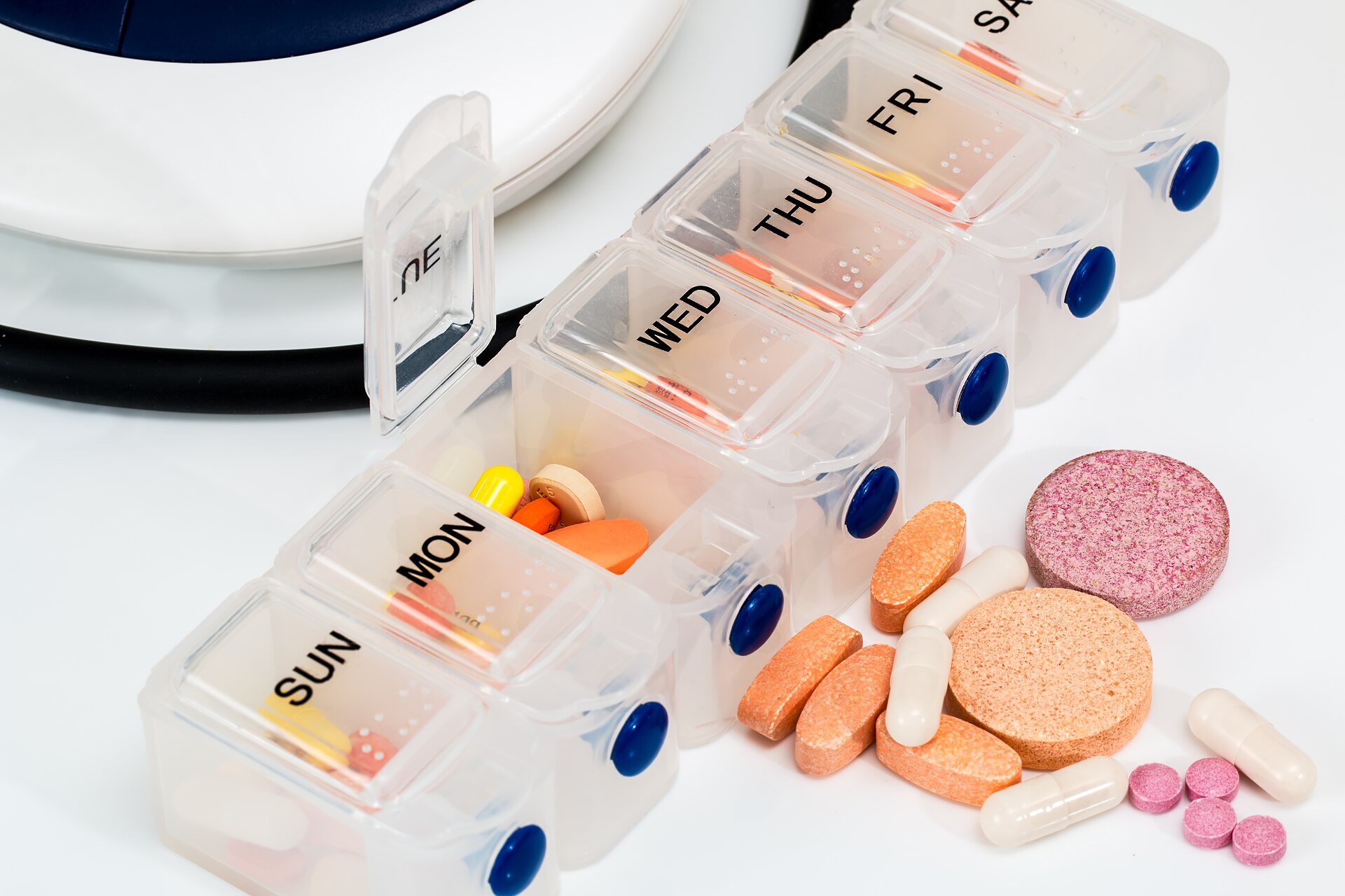 A weekly pill organizer with colourful tablets and capsules spilling out beside it