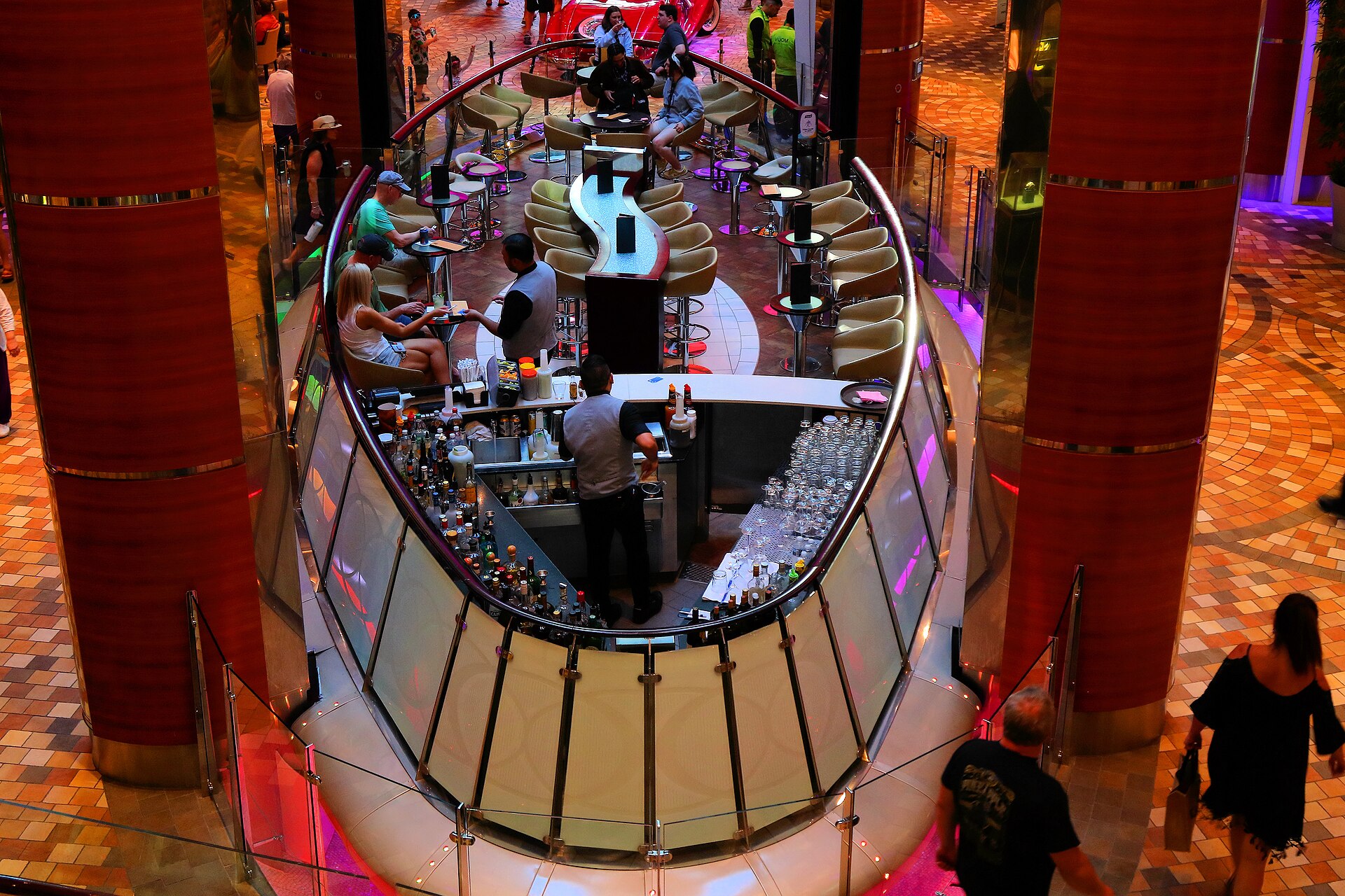 Bartender serving guests at the Rising Tide Bar above the Royal Promenade on Allure of the Seas