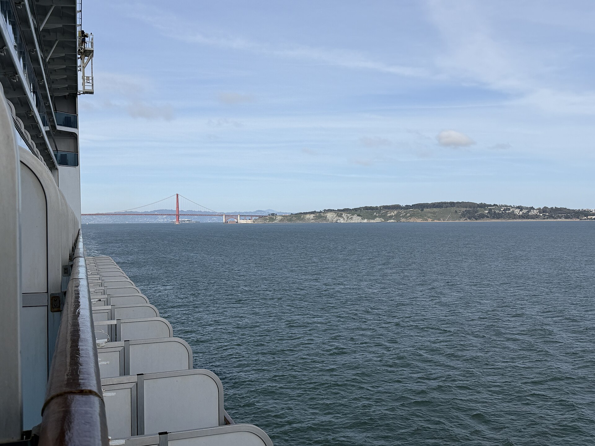 A row of Ruby Princess balconies along the ship's side with a flat horizon and the Golden Gate Bridge in the distance