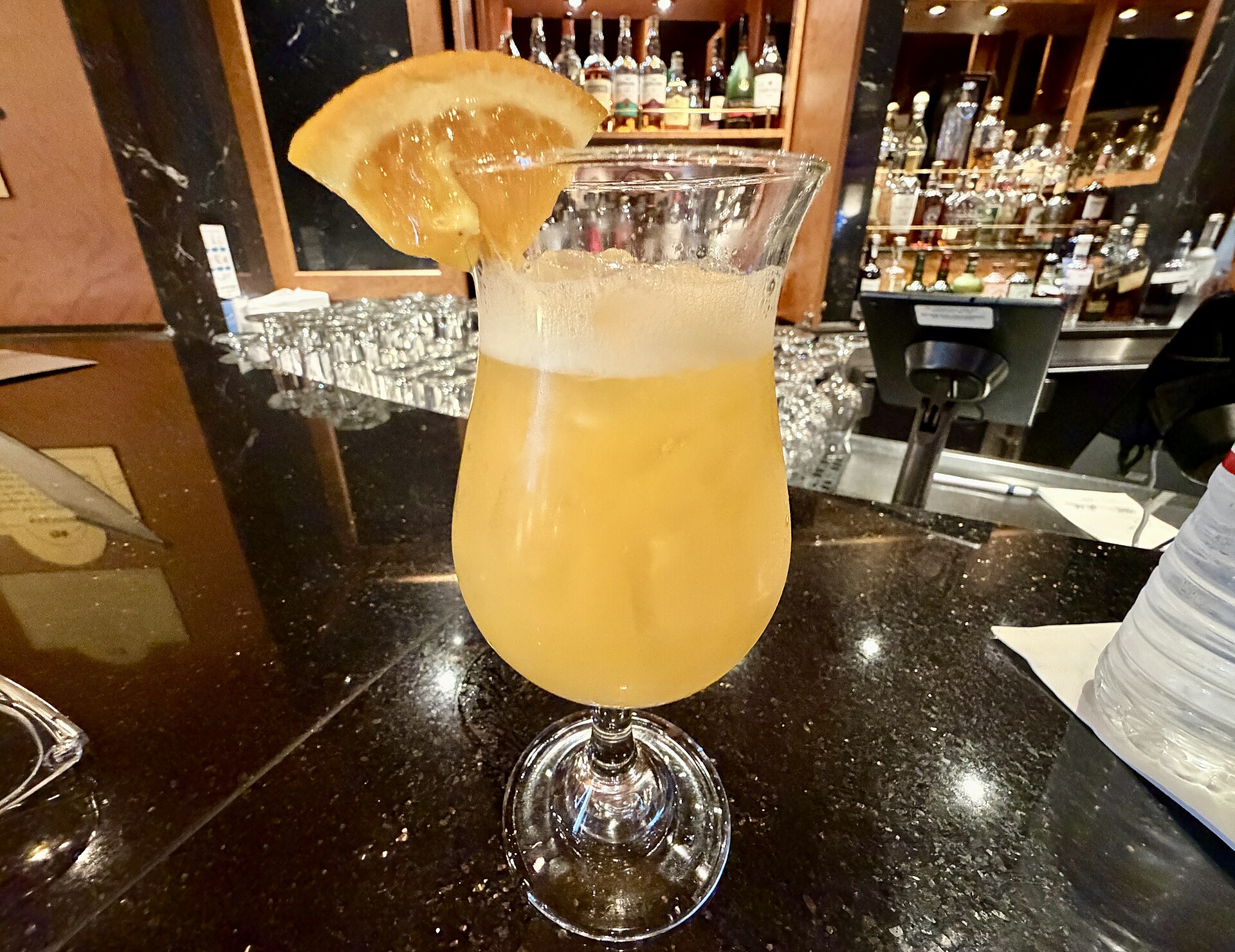 Passionfruit margarita with an orange slice on the bar at Crooners aboard Ruby Princess, with a card reader behind it