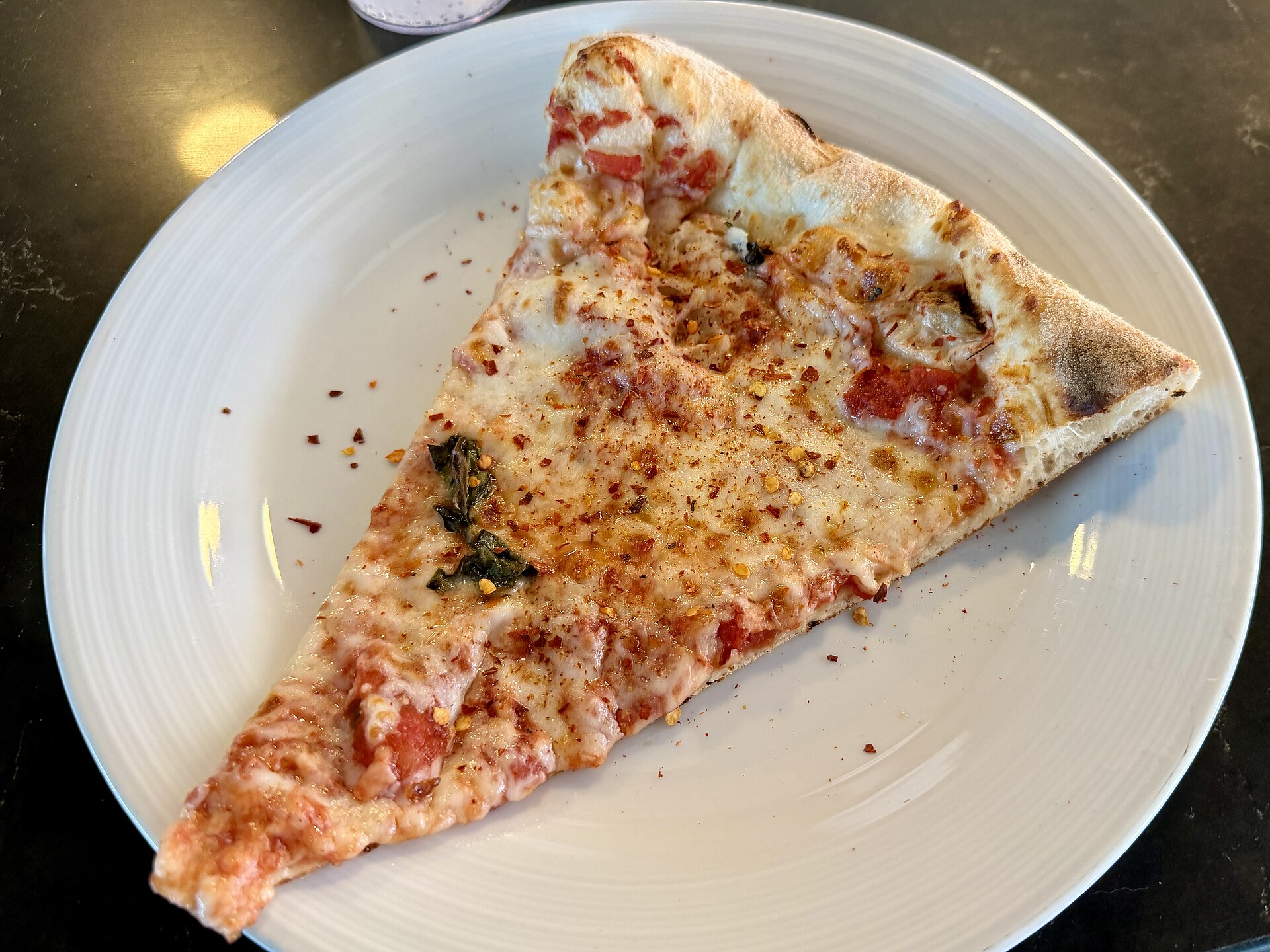 A slice of Margherita pizza on a white plate from the deck pizzeria on Ruby Princess