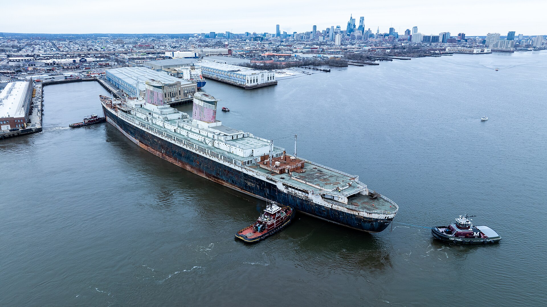Aerial view of tugboats guiding the SS United States away from Pier 80 on the Delaware River in Philadelphia