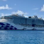 Star Princess at anchor in bright blue water under a blue sky with white clouds off Princess Cays