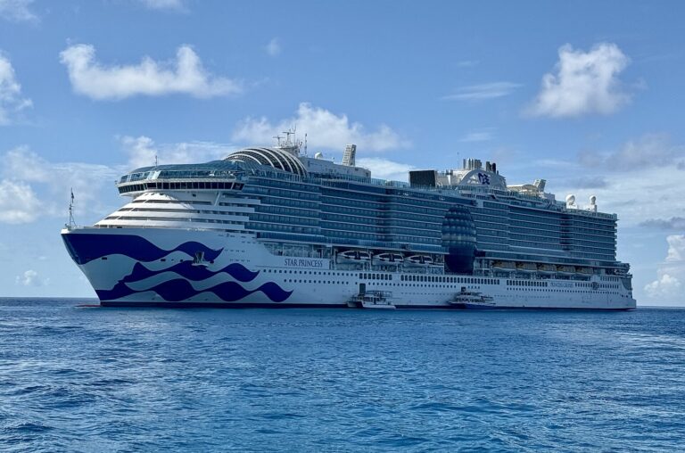 Star Princess at anchor in bright blue water under a blue sky with white clouds off Princess Cays