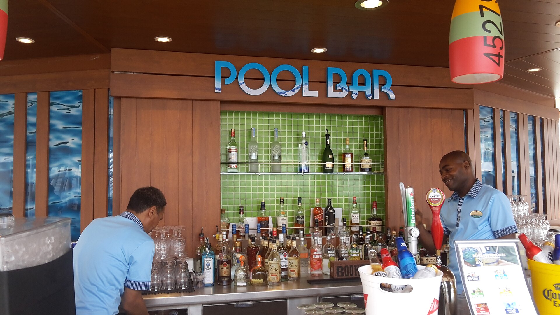 Bartenders behind the Pool Bar on Royal Caribbean's Symphony of the Seas, with bottles on green-tiled shelves