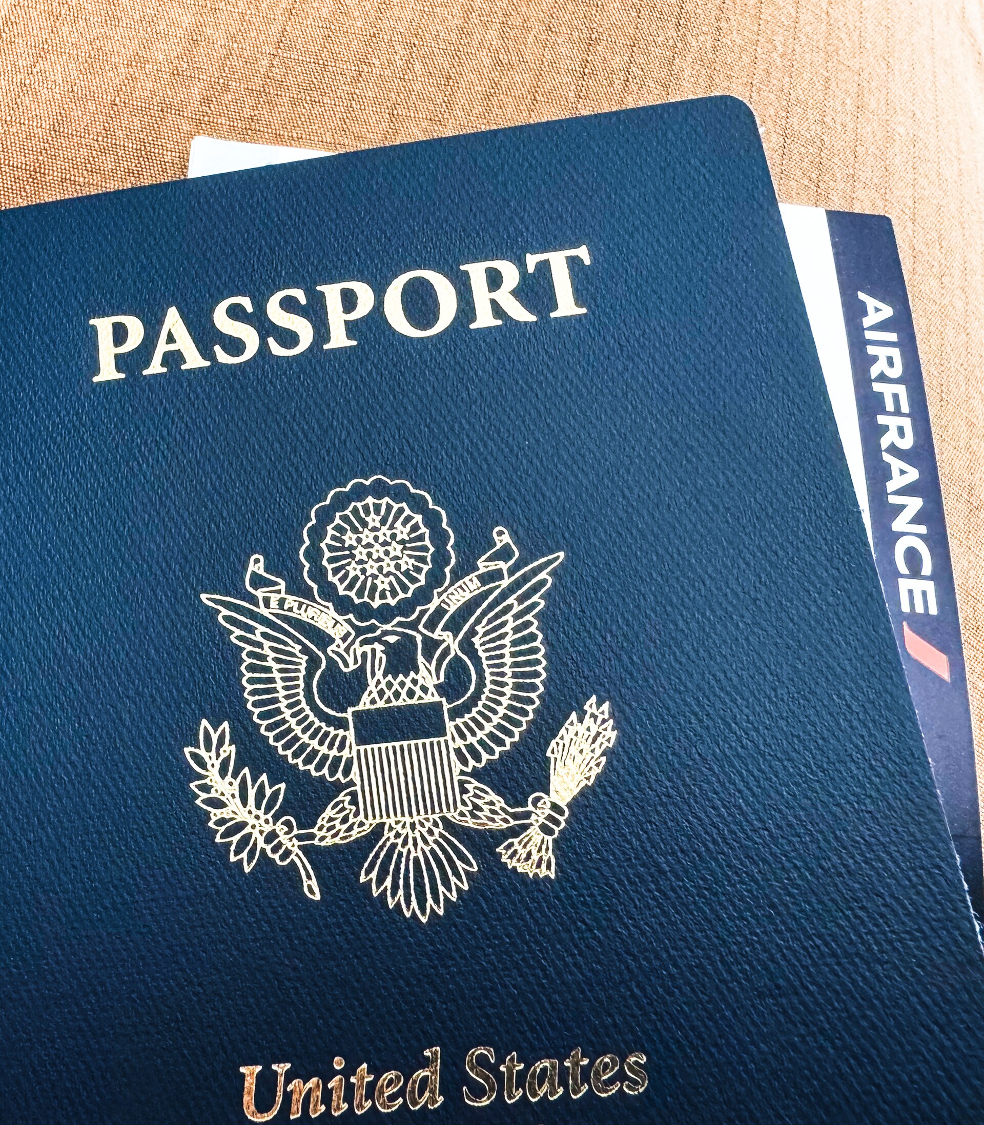 A navy blue United States passport with a gold eagle on the cover and an airline boarding pass tucked inside