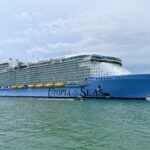Royal Caribbean's Utopia of the Seas sailing out through the Port Canaveral channel under a blue sky