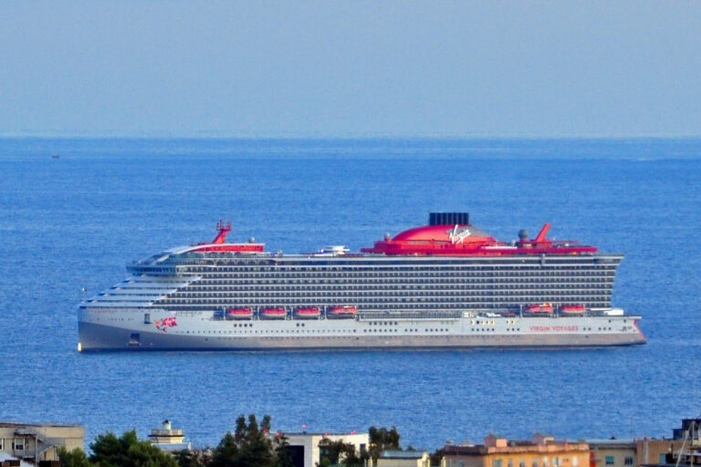 Virgin Voyages cruise ship Scarlet Lady sailing on a deep blue sea, with her red funnel and Virgin logo