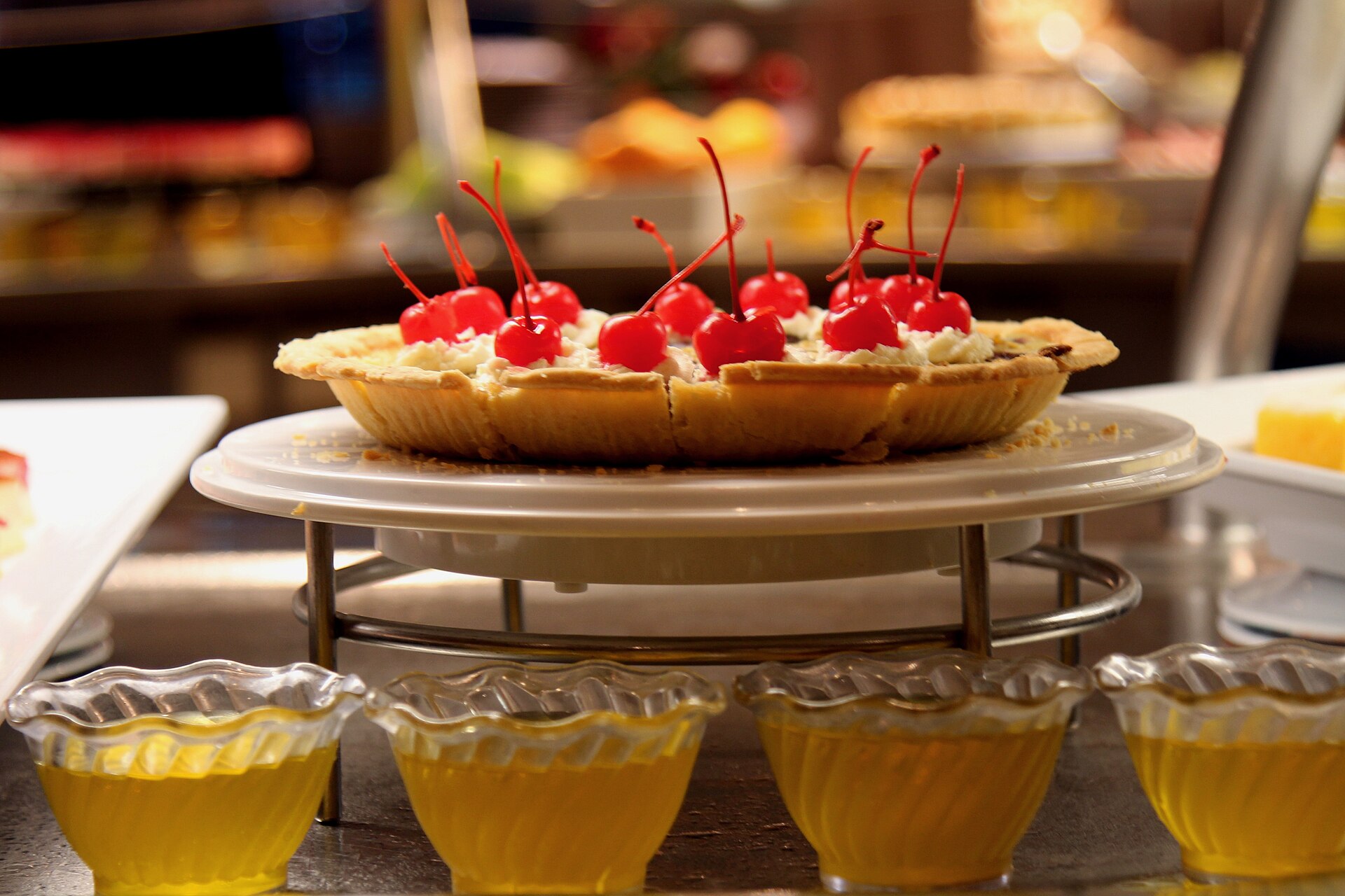 A cherry-topped tart and small bowls of yellow jelly on the dessert counter of the Windjammer buffet